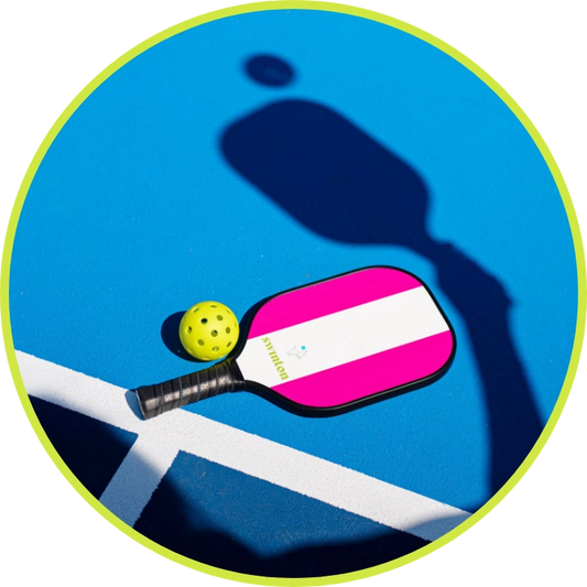 Swinton pickleball paddle + ball laying on court.