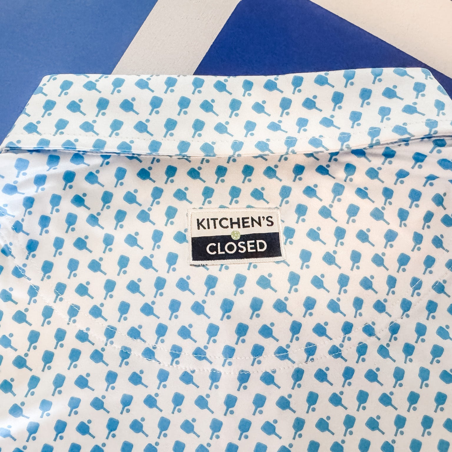 Shirt with blue pattern and 'Kitchen's Closed' label on a blue background