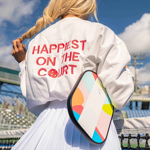 Female pickleball player wearing jacket reading "happiest on the court."