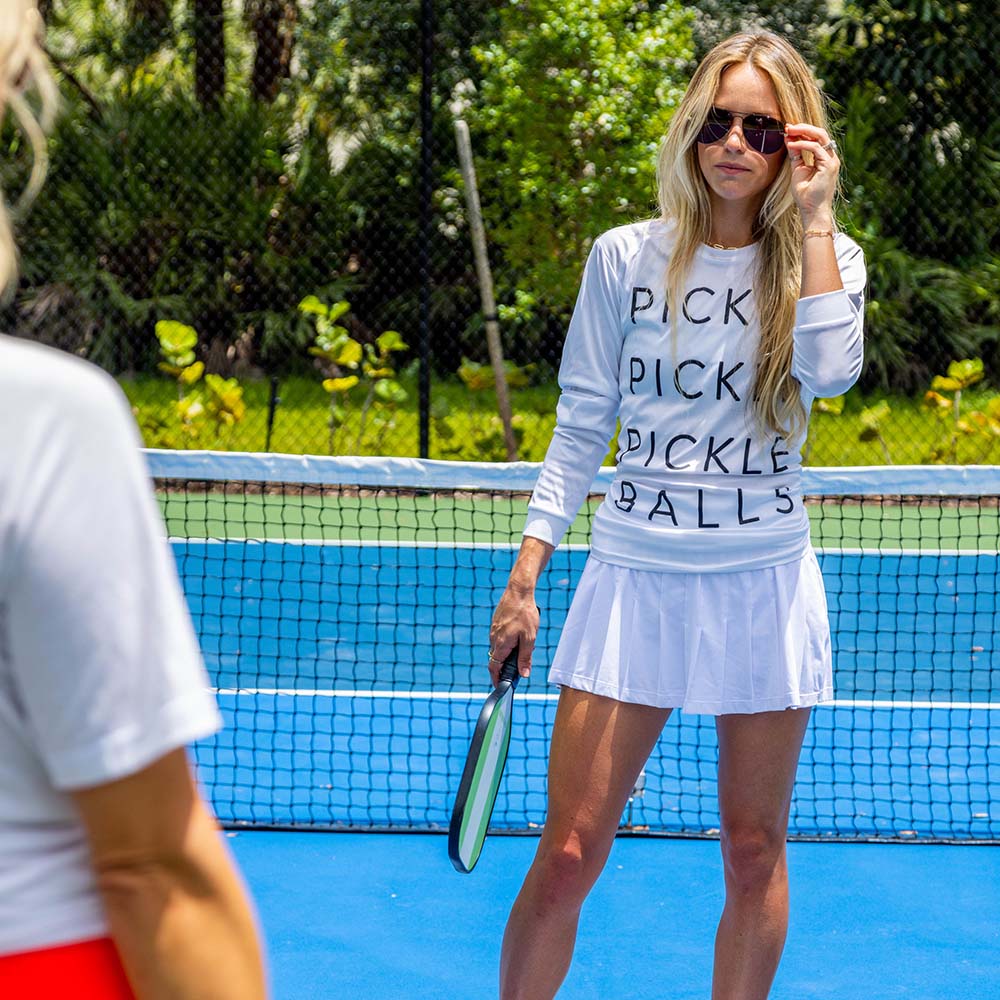 woman playing pickleball wearing picklepicklepickleballs long sleeve shirt